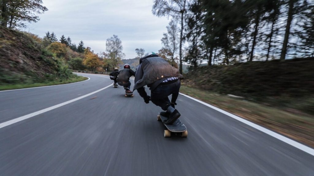 Longboard riders moving at speed on a road