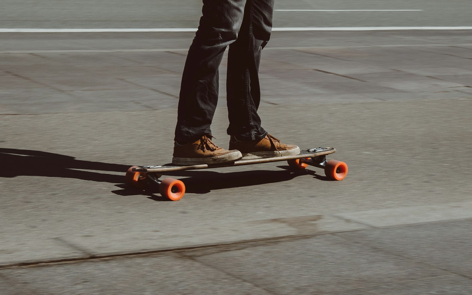Rider paseando y haciendo carving en longboard por una calle soleada